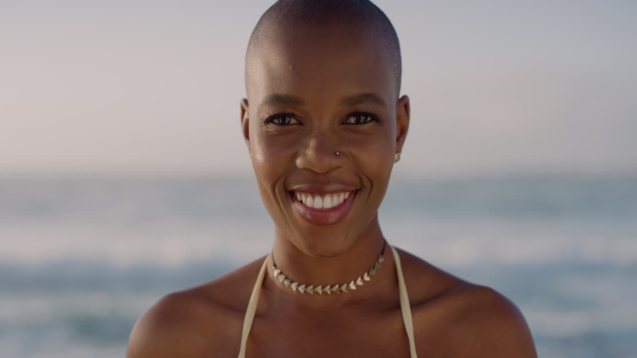 portrait of happy african american woman smiling enjoying summer vacation on warm sunny beach background slow motion