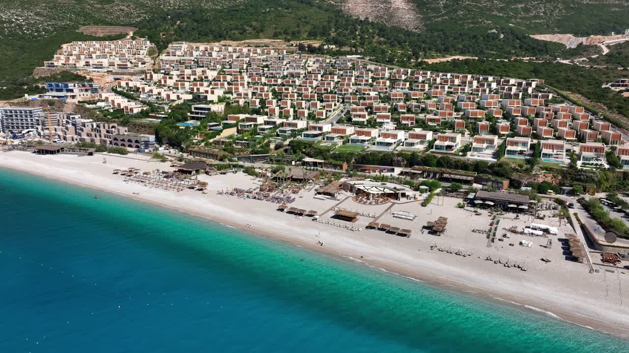 Drone of Palase beach and luxury coastal developments under clear summer sky in Albania
