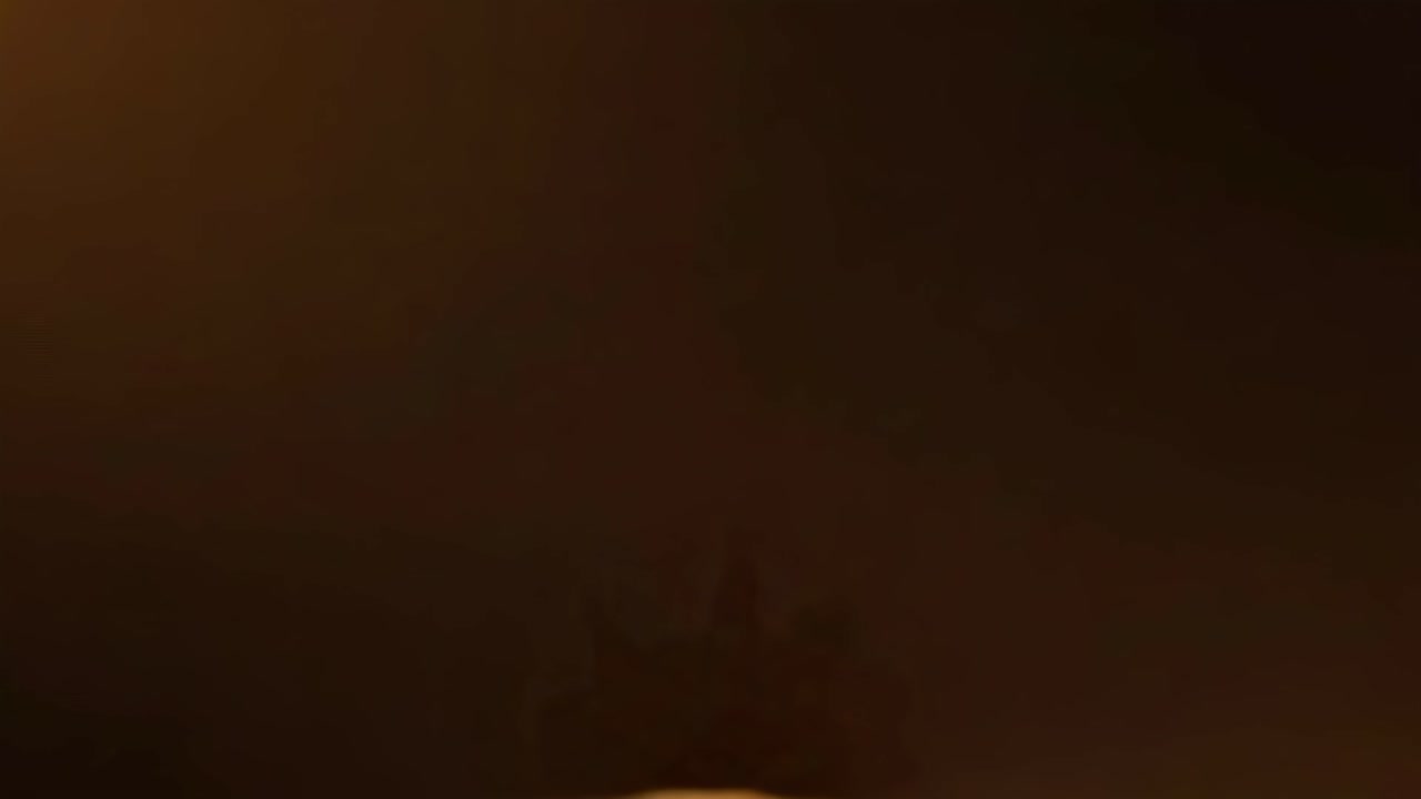 Golden particles explode in slow motion, captured from a low angle in this dynamic video