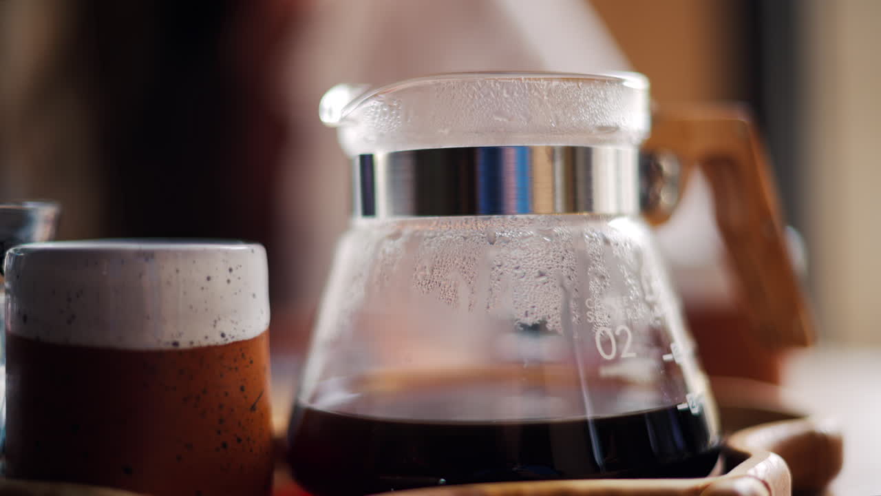 Close up of a glass coffee pot and a cup standing on a wooden tray