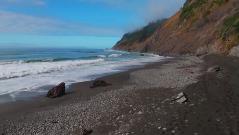 waves crashing black sand rugged coastline sunny morning blue sky mist fog layer usal beach campground lost coast trail californi pacific ocean pnw nor cali boulders rocks mountainside static motion
