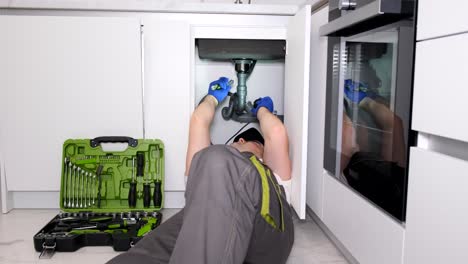 a worker in protective work clothes is doing plumbing work replacing an old broken sink filter a worker in protective work clothes is doing plumbing work replacing an old broken sink filter call the master plumber to the house