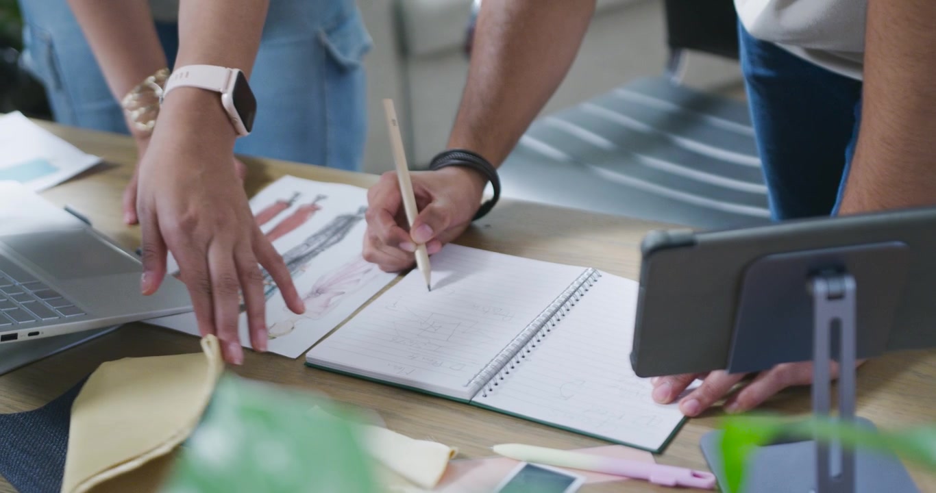 Dopo la revisione dello schizzo, i designer stanno allineando il tessuto e prendendo appunti su un blocco note sul tavolo per il design finale.