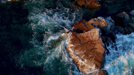 rocky shore with waves crashing on it in genoa, liguria, italy, captured at sunset