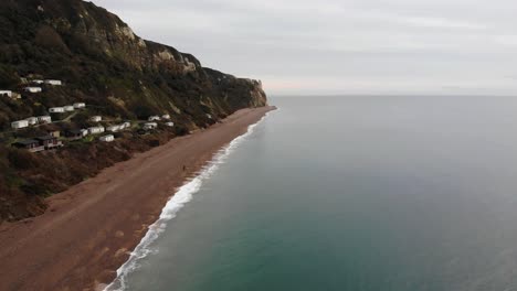 4k smooth aerial shot flying above the oceans rolling waves and panning slowly towards the mountains