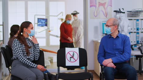 people with masks discussing sitting on chairs keeping distance