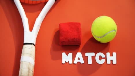 Close-up-of-tennis-ball,-wrist-band-and-racket-on-red-floor-4k