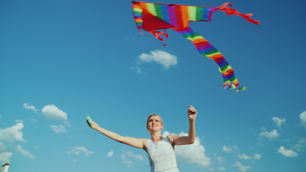 순수한 푸른 하늘 4k 비디오를 배경으로 어린 시절의 행복한 여성이 연을 가지고 놀고 있습니다.