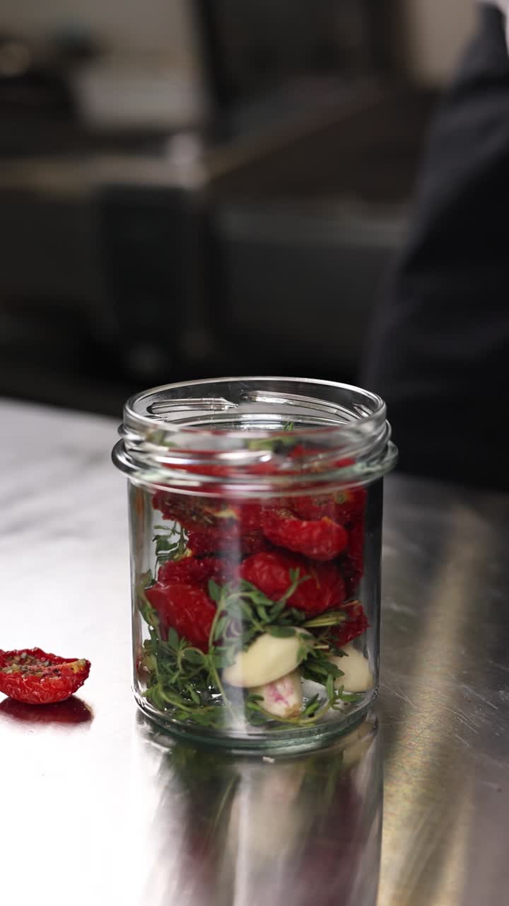 Chef preparing sun-dried tomatoes in jars
