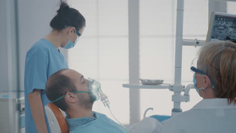 trabajador de atención oral dando máscara de oxígeno con anestésico al paciente