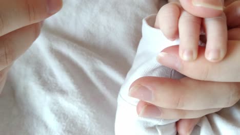 bebé recién nacido, padre madre cortando manos diminutas, primer plano de ángulo alto, cama interior