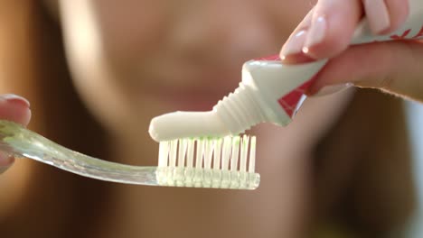 Morning-teeth-brushing.-Close-up-woman-hands-squeezing-toothpaste-on-toothbrush