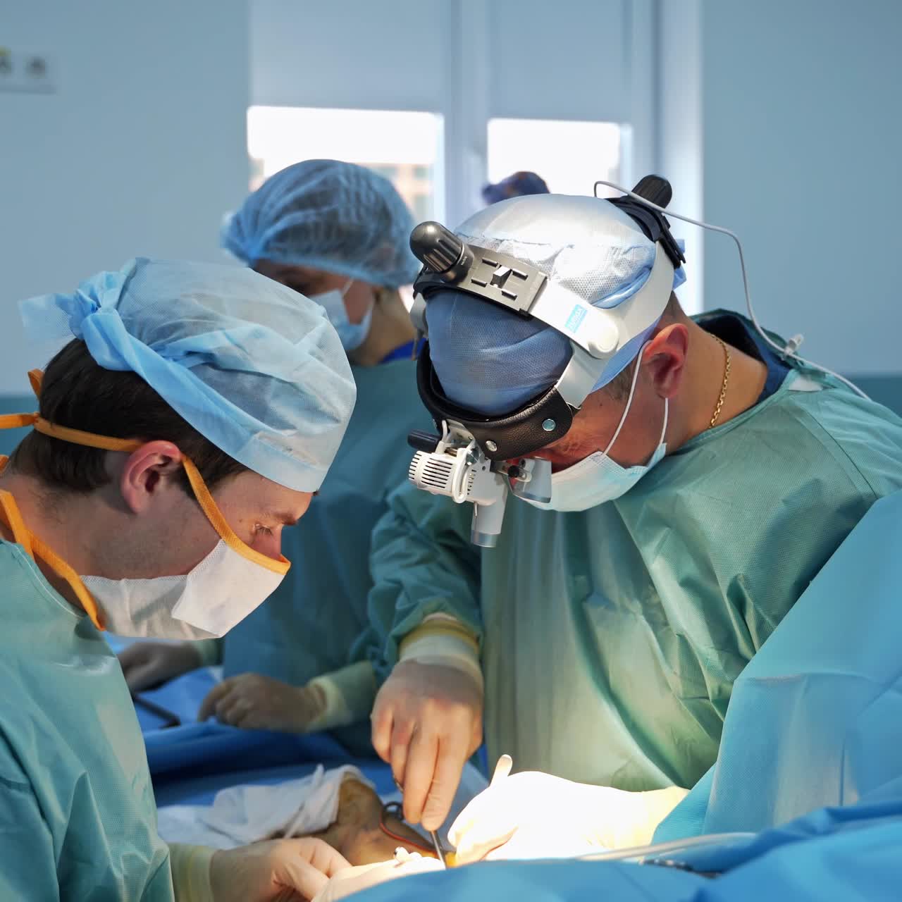 Team surgeons perform operation on patient's arm. Surgical invasion in highly-equipped modern operational theatre