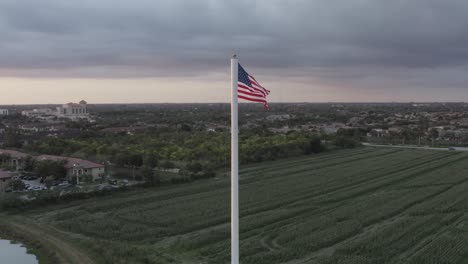 Excelente-Toma-Aérea-De-La-Bandera-Americana-Ondeando-Sobre-Campos-Agrícolas-En-El-Sur-De-Florida