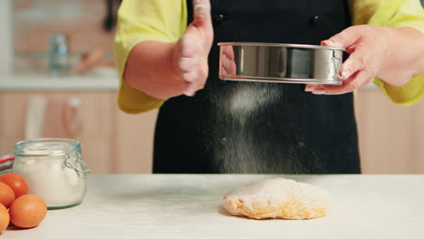 sifting flour on dough using metallic sieve