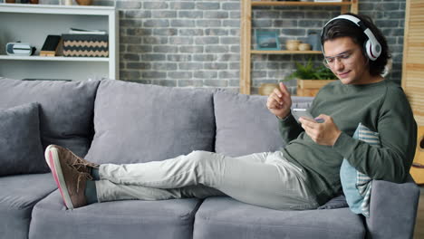 hombre relajándose en el sofá con auriculares y teléfono