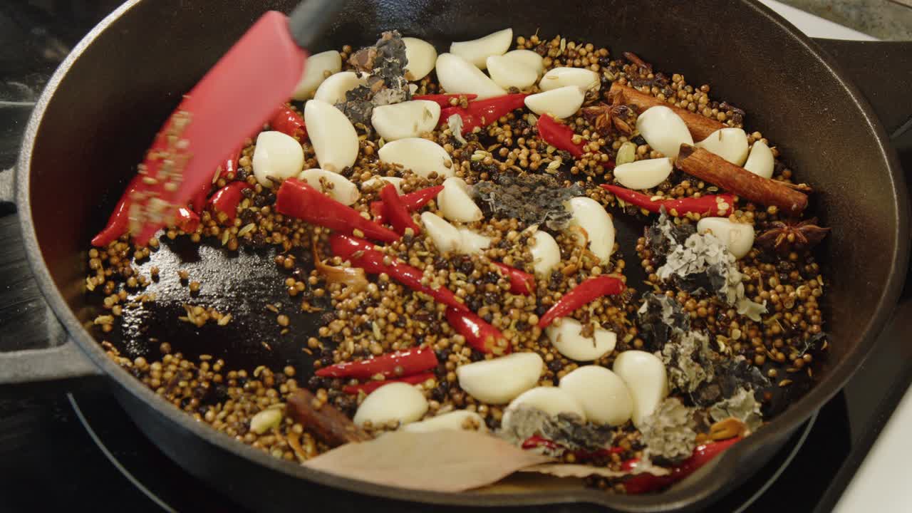 Ingredienti per masala caldi, speziati e aromatici mescolati in una padella di ghisa calda.