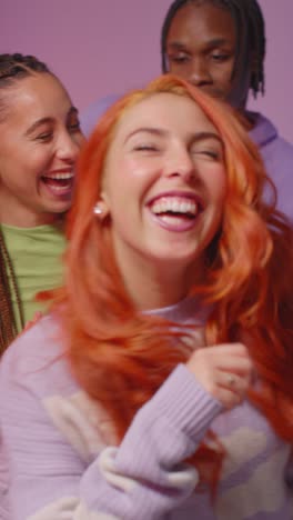 Vertical-Video-Studio-Shot-Of-Smiling-Gen-Z-Friends-Dancing-At-Party-Against-Pink-Background