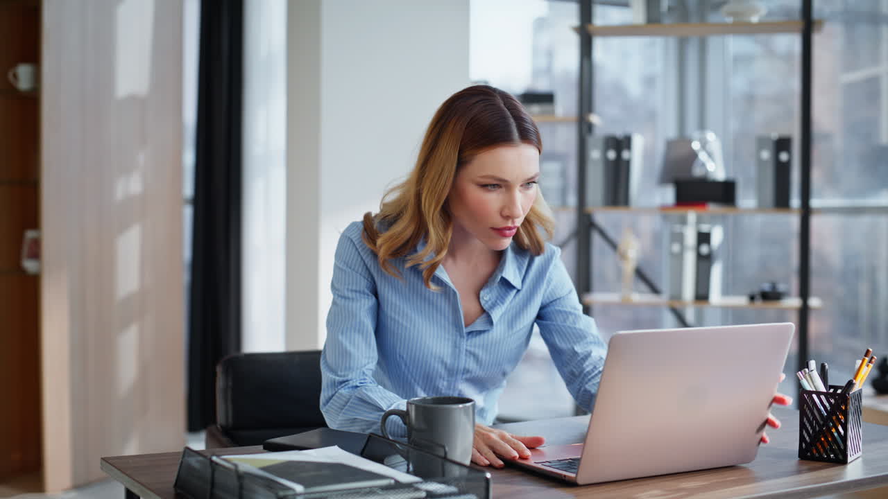 Donna d'affari sicura di sé inizia la giornata lavorativa, seduta in ufficio con caffè, primo piano