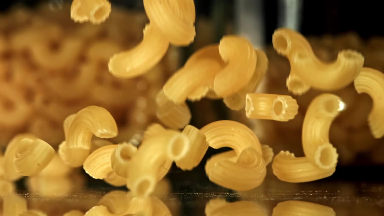 Pasta di maccheroni a gomito secchi che cadono al rallentatore