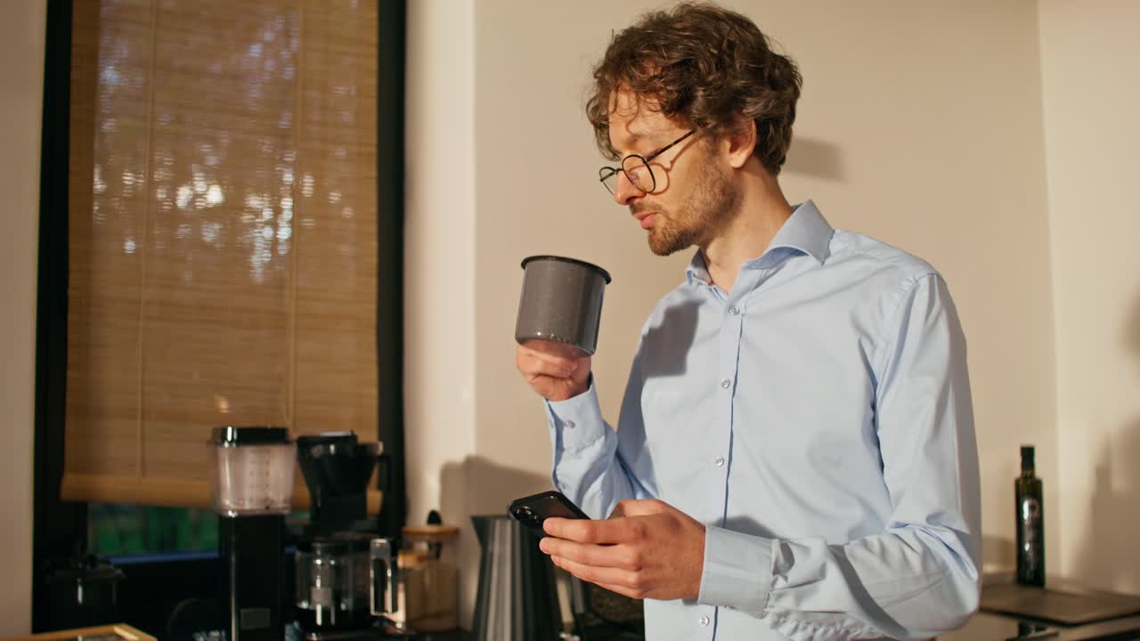 hombre usando el teléfono y bebiendo café en la cocina