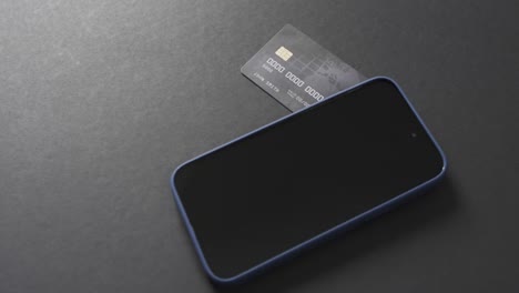 Video-of-smartphone-with-blank-screen,-boxes-and-credit-card-with-copy-space-on-grey-background