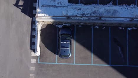vista aérea superior del coche azul estacionado en un aparcamiento al aire libre cubierto de nieve
