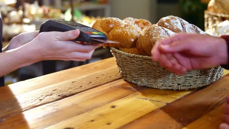 hombre haciendo un pago con tarjeta de crédito en una cafetería