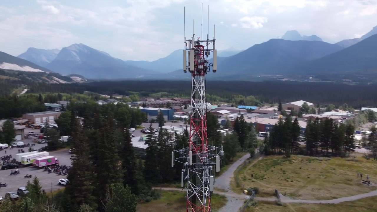 Torre per telefonia mobile in un paese di montagna, ripresa aerea con drone in volo circolare