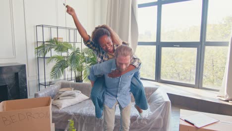 familia diversa de mujer se sienta en la espalda del hombre y agita las llaves del apartamento hipotecado