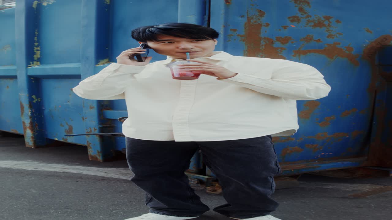 남자가 전화로 얘기하고 밖에서 스무시를 마시고
