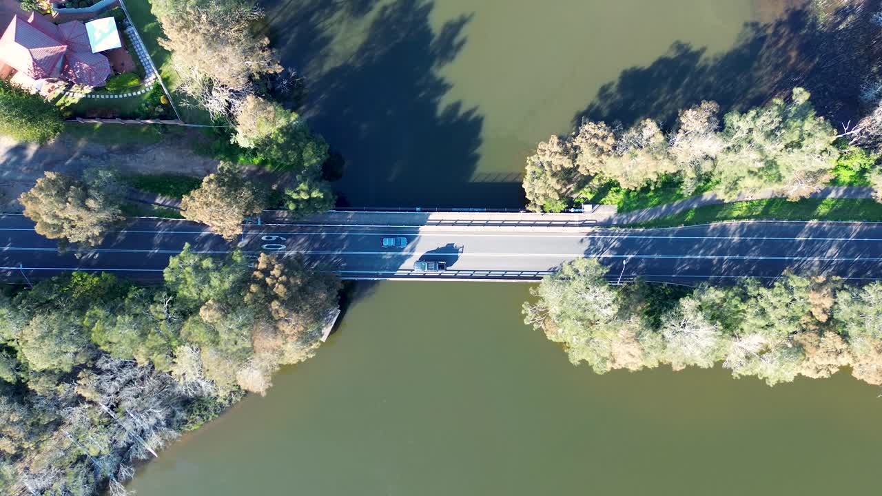 Drone aerial landscape of car vehicles driving across Avoca Beach bridge structure with surrounding trees on the creek lagoon and public walkway path Central Coast Australia travel scenery outdoors