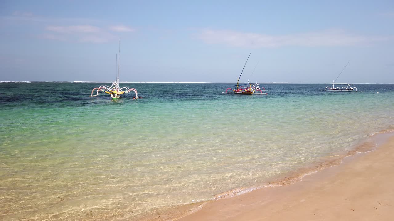 Nusa Dua beach filming with hand held camera landscape with ocean white sand and fishing traditional balinese boat anchored. Beautiful Bali Indonesia summer traveler ultimate destination