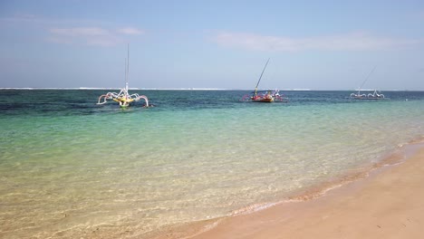 nusa dua beach filming with hand held camera landscape with ocean white sand and fishing traditional balinese boat anchored. beautiful bali indonesia summer traveler ultimate destination