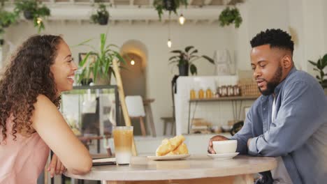 pareja feliz diversa pasando tiempo juntos en una cafetería, bebiendo café y hablando