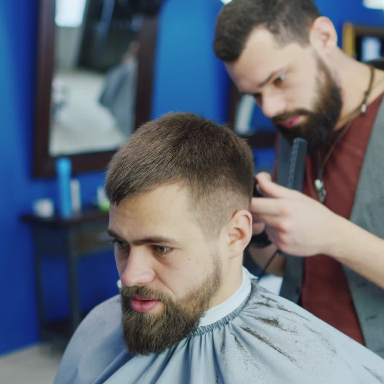 Venlig barber tørrer kundens hår i barbersalon 01.