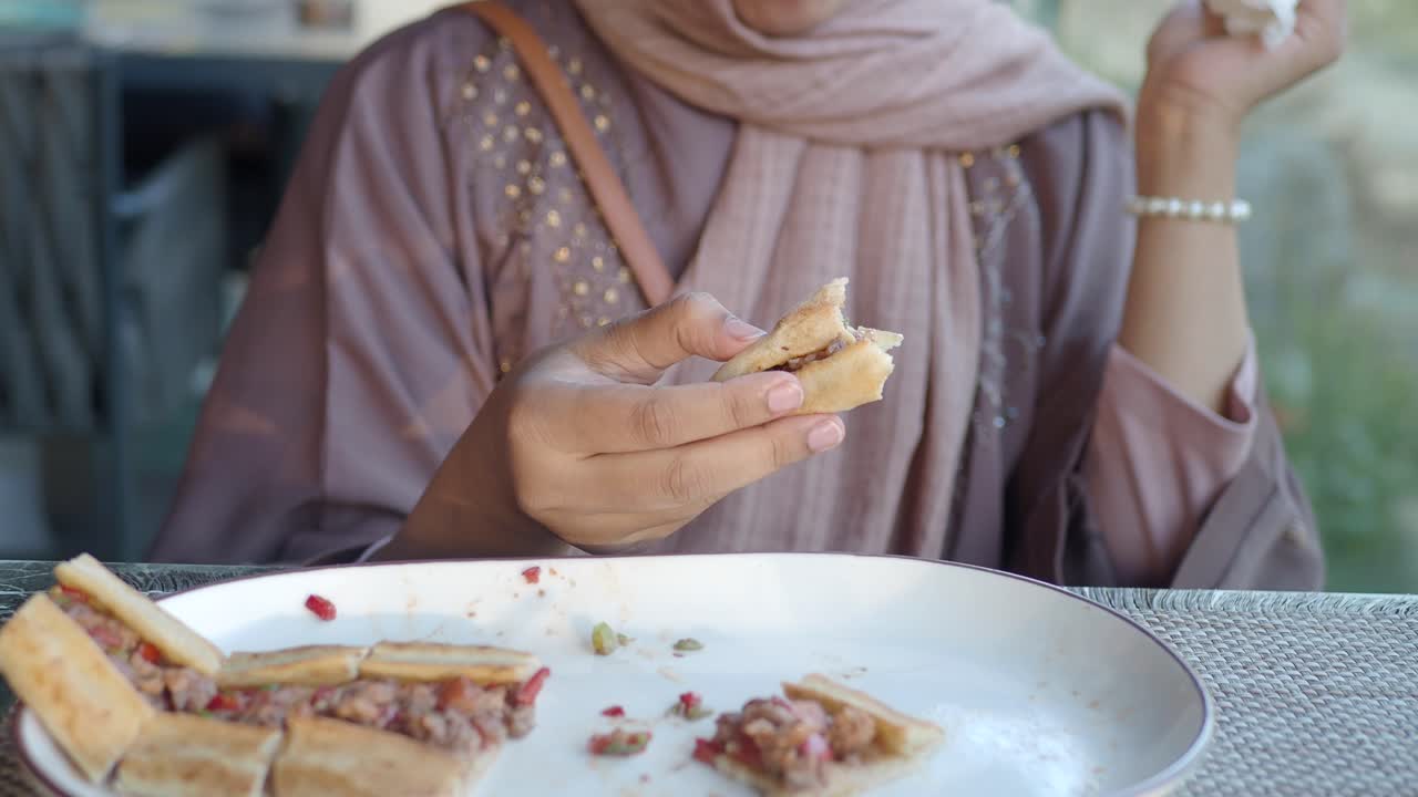 una mujer con hijab disfrutando de una deliciosa comida turca.