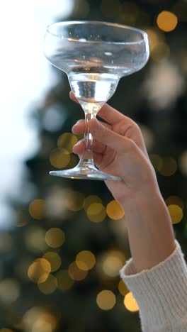 woman holding a cocktail glass in front of a christmas tree