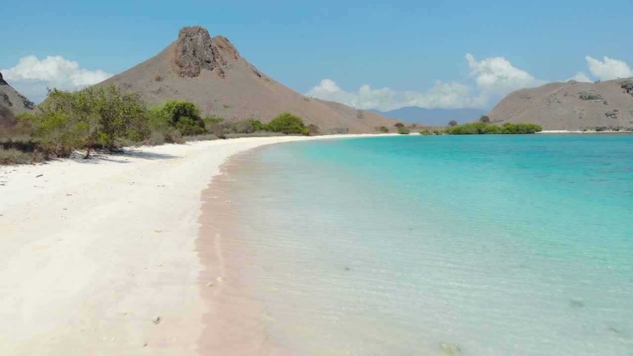 Flight over sandy beach and turquoise water of Pantai Merah On Padar Island in Komodo National Park, Indonesia