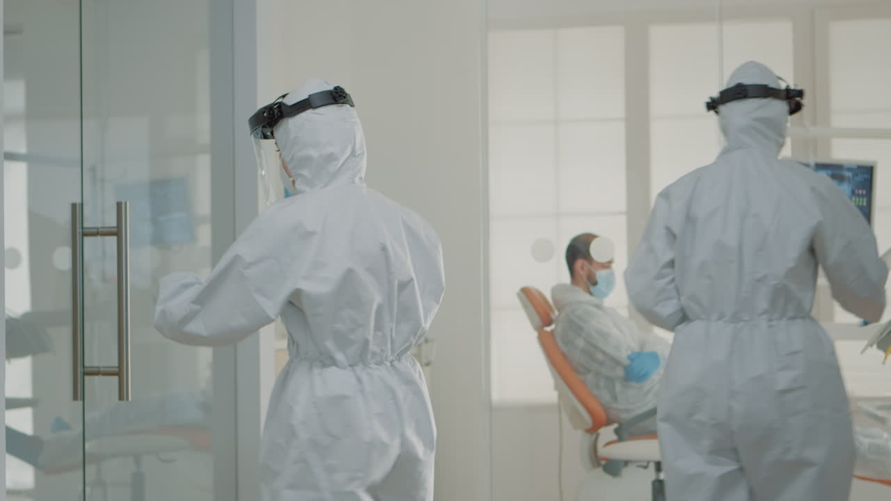 보호복을 입은 치과의사들이 의학에 대해 얘기하고 있습니다.