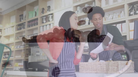 two co-workers checking order on tablet behind cafe counter, showing floating sales chart