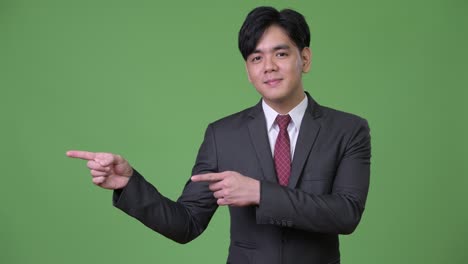 무언가를 보여주는 젊은 잘생긴 아시아 사업가