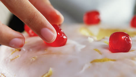 woman topping a fresh baked cake with cherry 4k