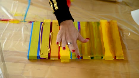 a woman using painters tape to finish her colorful stripes on a canvas