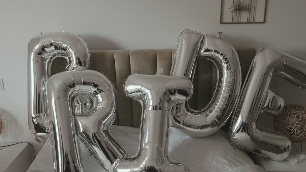 Globos metálicos con letras que forman la palabra bride sobre la cama
