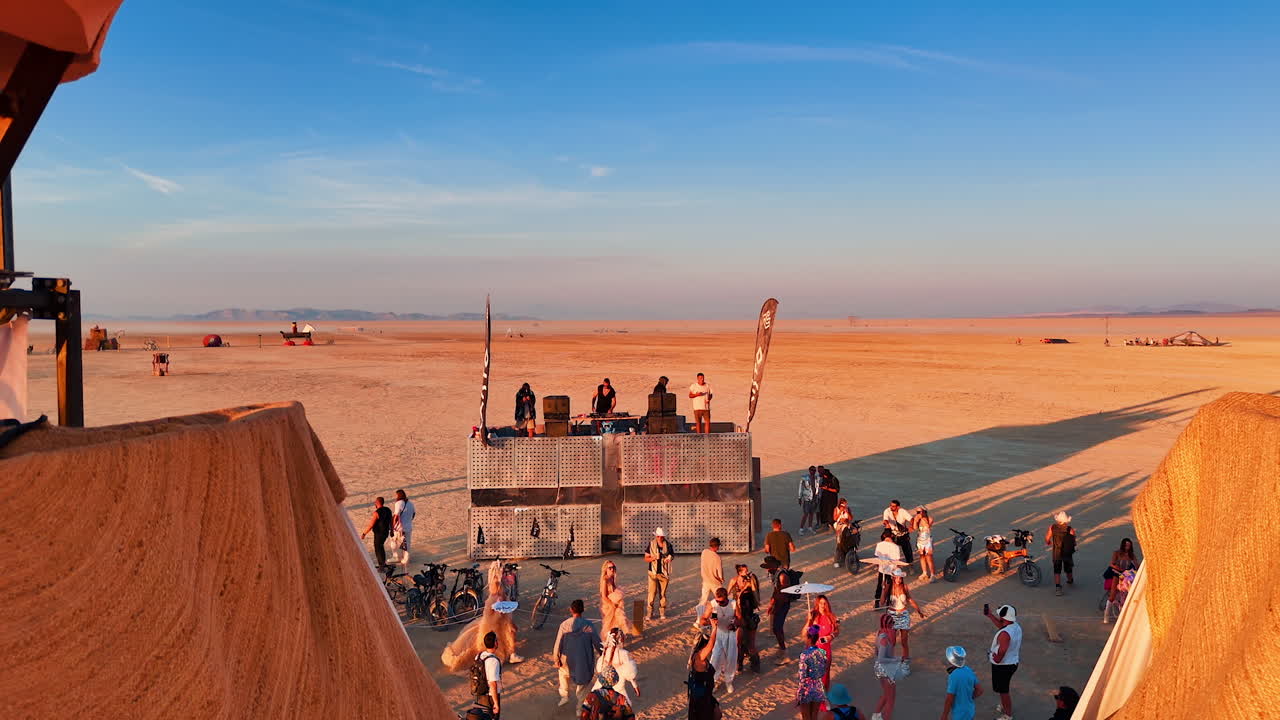 Dual head sculpture at desert gathering. Large constructed heads rise over visitors exploring the artistic installation under warm desert light