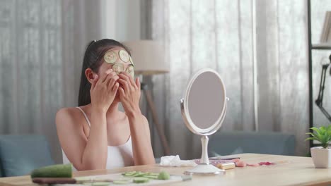 woman applying cucumber facial mask