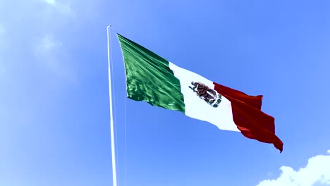 mexican flag waving with a blue sky in the back
