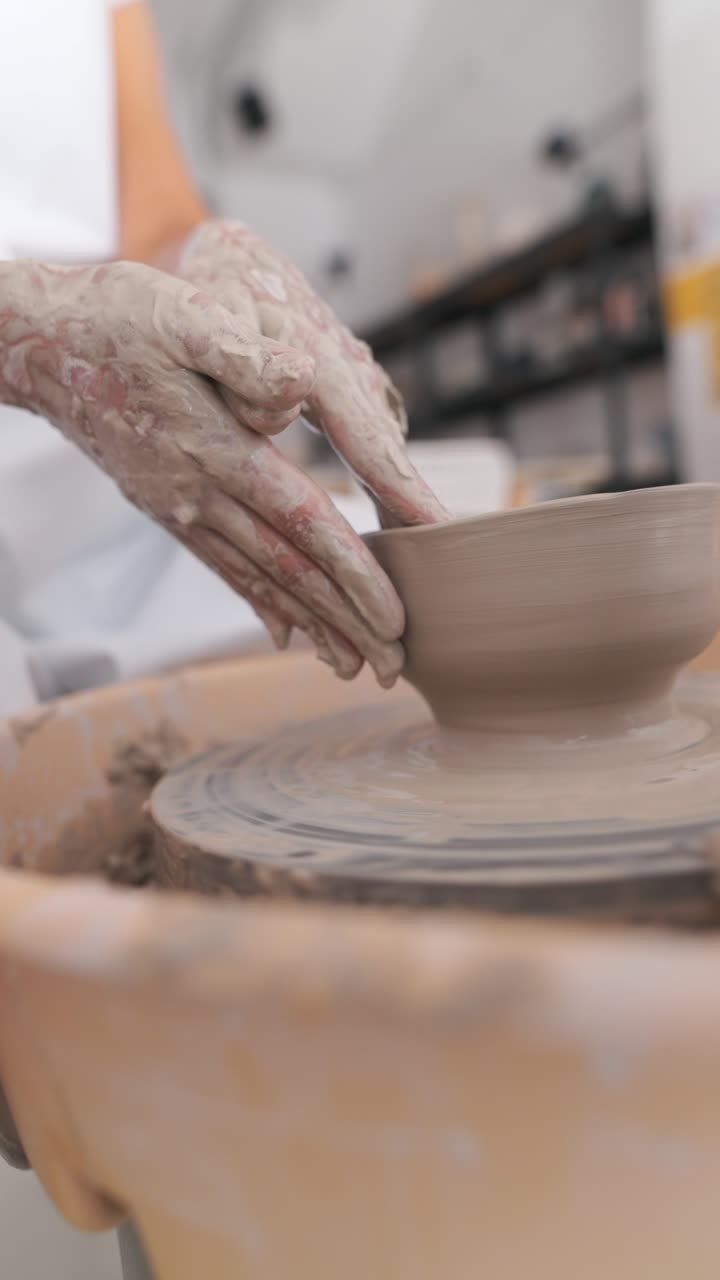 Hands shaping a clay pot on a potter's wheel