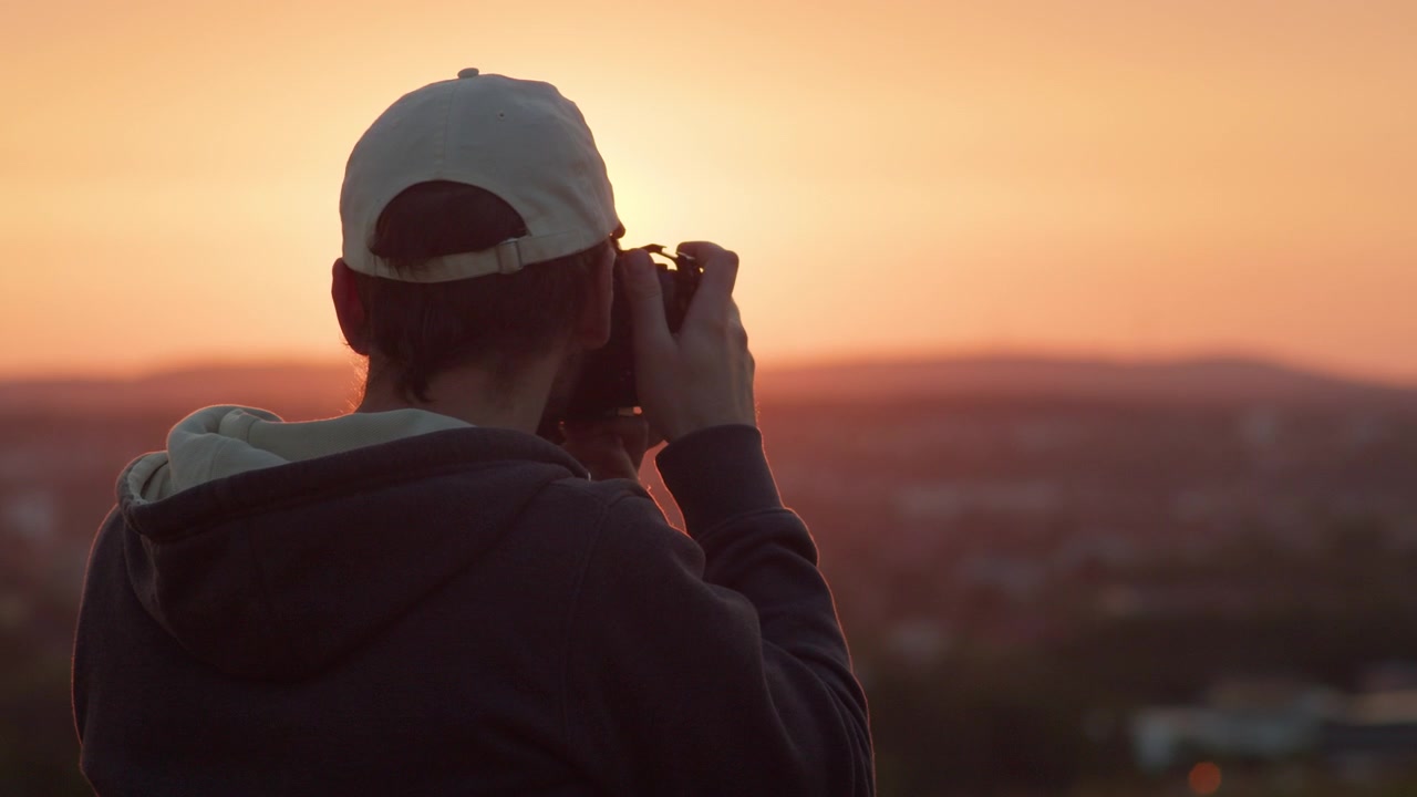 Close-up de um fotógrafo de paisagens capturando fotos de um belo pôr do sol dourado